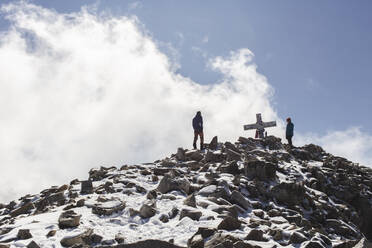 Freunde stehen in der Nähe des Gipfelkreuzes auf dem Berg - PCLF00869