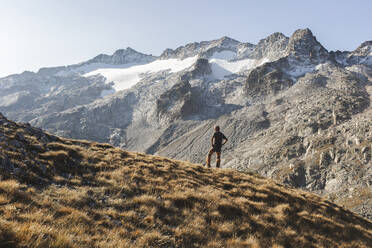 Man standing with hands on hip in front of mountain - PCLF00873