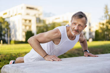 Mature man doing push-ups in park - DIGF20893