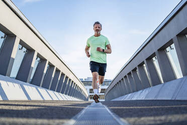 Mature athlete jogging on footbridge - DIGF20936
