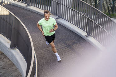 Active sportsman jogging on footbridge - DIGF20938