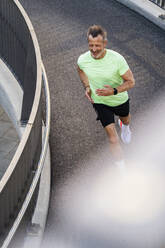 Active sportsman jogging on footbridge - DIGF20939