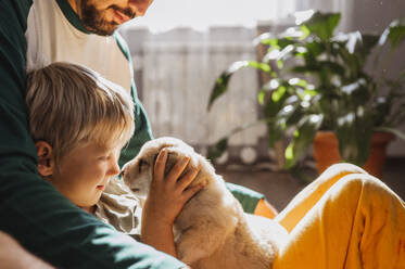 Blond boy playing with cute mixed breed puppy at home - ANAF02267