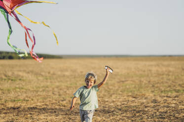 Happy boy flying kite and running in meadow - ANAF02300