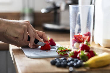 Hände einer Frau, die Erdbeeren mit einem Messer schneidet - WPEF07733