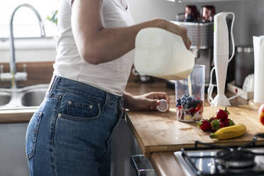 Frau bereitet gesunden Milchshake in der Küche zu Hause zu - WPEF07734