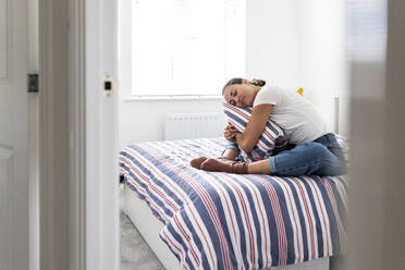 Woman with eyes closed hugging pillow at home - WPEF07776