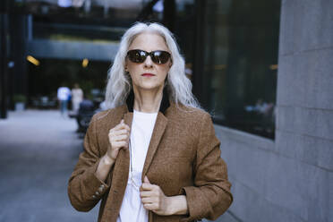 Mature businesswoman wearing brown jacket standing on street - YBF00264