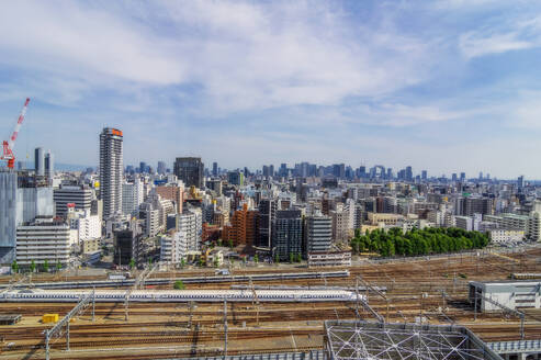 Japan, Osaka Prefecture, Osaka City, Train waiting at station with downtown skyscrapers in background - THAF03259
