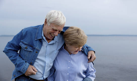 Älteres Paar lachend mit Arm um am Strand - MBLF00006