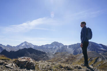 Man with backpack standing near mountain under sky - NJAF00588