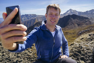 Happy man taking selfie near mountain on sunny day - NJAF00590