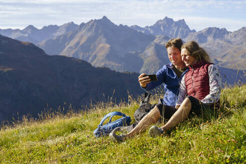 Happy couple taking selfie through smart phone on sunny day - NJAF00595