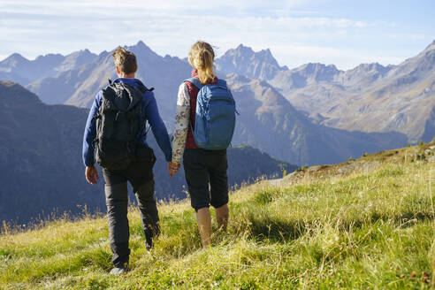 Paar hält sich an den Händen und schaut auf die Berge an einem sonnigen Tag - NJAF00598