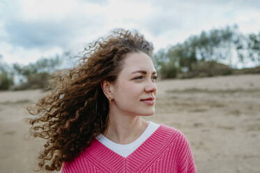 Happy woman with curly hair at beach - ANAF02312