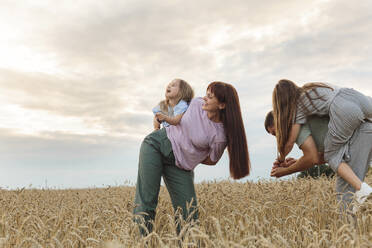Smiling parents and daughters having fun in field under sky - LLUF01116