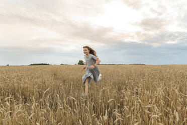 Happy girl running amidst field under sky - LLUF01120