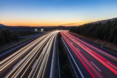 Deutschland, Baden-Württemberg, Kirchheim unter Teck, Fahrzeug-Lichtspuren auf der Bundesautobahn 8 in der Abenddämmerung - WDF07420