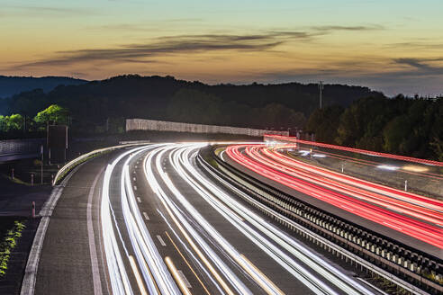 Deutschland, Baden-Württemberg, Kirchheim unter Teck, Fahrzeug-Lichtspuren auf der Bundesautobahn 8 in der Abenddämmerung - WDF07422