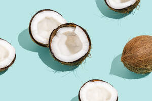 Halbierte frische Kokosnüsse vor blauem Hintergrund - FLMF01027