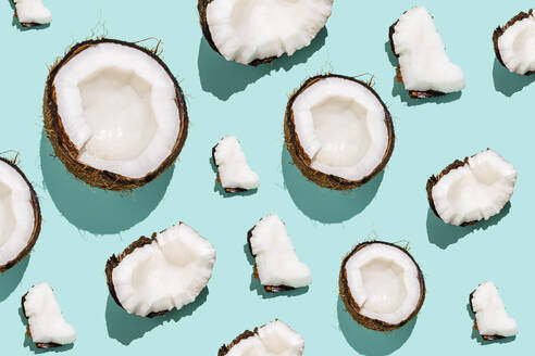 Broken slices of coconuts arranged against blue background - FLMF01028