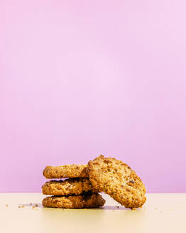 Raisin cookies stacked against pink colored background - FLMF01033