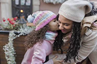 Mädchen küsst Mutter auf die Wangen auf dem Weihnachtsmarkt - VIVF01078
