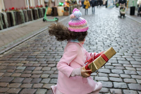Glückliches Mädchen hält Geschenkbox und läuft auf der Straße - VIVF01092
