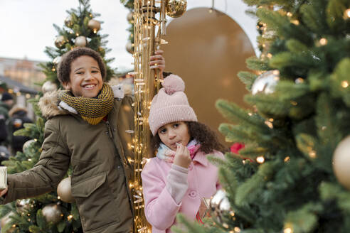 Ein glückliches Geschwisterpaar erfreut sich an den Weihnachtsbäumen auf dem Markt - VIVF01098