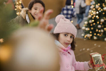 Mädchen mit Geschenkbox und Bruder auf dem Weihnachtsmarkt - VIVF01100