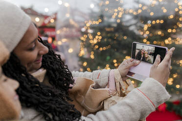 Mother taking selfie with son through smart phone at Christmas market - VIVF01117