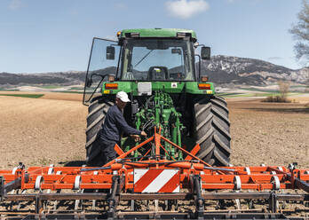 Landwirt stellt den Pflug eines Traktors auf einem Feld ein - PBTF00344