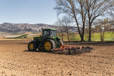 Landwirt pflügt Feld mit Traktor an einem sonnigen Tag - PBTF00345