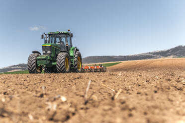 Landwirt pflügt Feld mit Traktor unter Himmel - PBTF00346