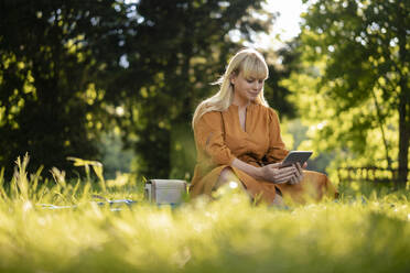 Frau benutzt Tablet-PC im Park an einem sonnigen Tag - JOSEF21466