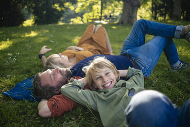 Happy boy with parents relaxing in park - JOSEF21468