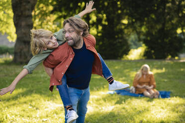 Happy father giving piggyback ride and enjoying with son in park - JOSEF21490