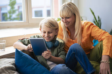 Happy woman with son using tablet PC at home - JOSEF21506