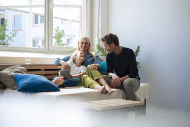 Glückliche Eltern mit Sohn, der zu Hause auf dem Sofa sitzt - JOSEF21534
