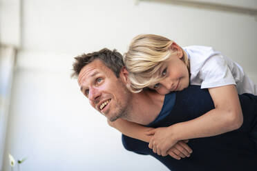 Lächelnder Vater und Sohn genießen vor der Wand zu Hause - JOSEF21548