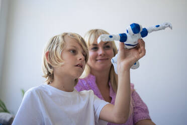 Smiling mother and son playing with robot at home - JOSEF21580