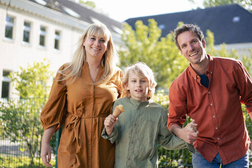 Glückliche Eltern mit Sohn, der an einem sonnigen Tag eine Eistüte hält - JOSEF21583