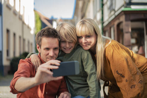 Happy father taking selfie with woman and son through smart phone - JOSEF21597