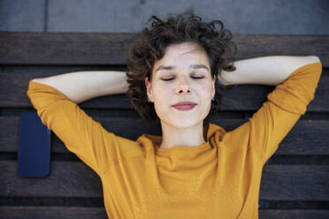 Woman with eyes closed lying on bench - JOSEF21605