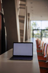 Laptop mit leerem Bildschirm auf einem Tisch in einer Büro-Cafeteria - JOSEF21617