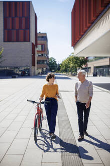 Lächelnde Frau im Gespräch und beim Spaziergang mit einem älteren Mann an einem sonnigen Tag - JOSEF21618