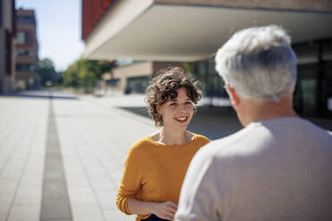 Lächelnde Frau im Gespräch mit älterem Mann an einem sonnigen Tag - JOSEF21620