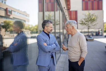Senior businessmen discussing together near building at footpath - JOSEF21630