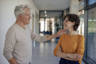 Smiling businessman supporting young businesswoman in office - JOSEF21653