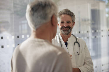 Smiling senior doctor talking to man in hospital - JOSEF21662